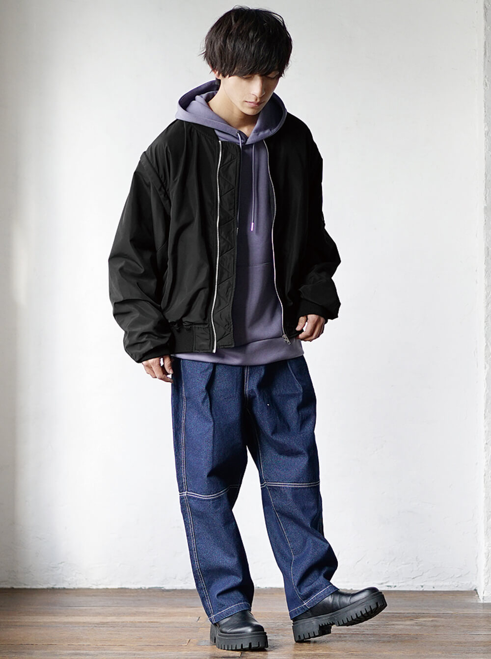 Oversized black bomber layered over a purple hoodie with wide baggy denim